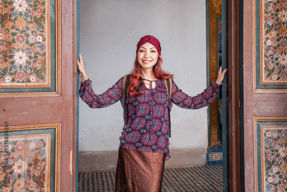 Young woman tourist opening a big decorated wooden door in a traditional Moroccan building