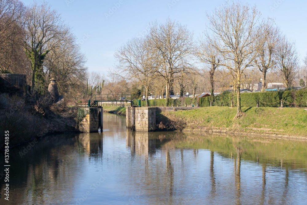 Obraz premium Reflections of the ramparts and trees in Bergues, northern France