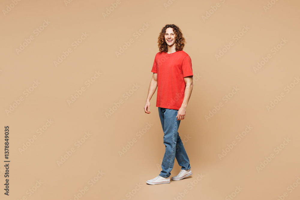 Full body side view young fun Caucasian man he wear red t-shirt casual clothes walking going strolling look camera isolated on plain pastel light beige background studio portrait. Lifestyle concept Full body side view young fun Caucasian man he wear red t-shirt casual clothes walking going strolling look camera isolated on plain pastel light beige background studio portrait. Lifestyle concept