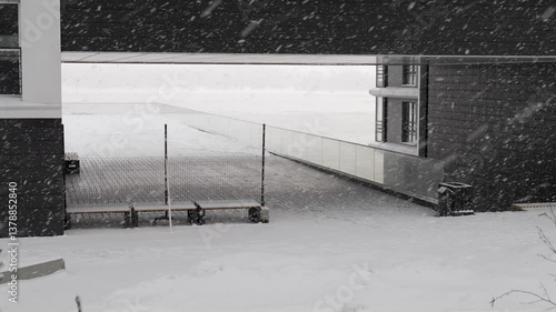 Snowfall against the background of the arch of a modern building. Blizzard and snowdrifts in the city.