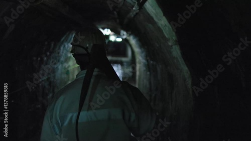 miner walks in tunnel with pickaxe on his shoulder