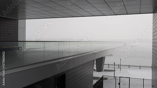Modern architecture on the embankment under snowfall. Arch with an observation deck in the building in winter.