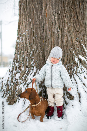 little girl holding a dog on a leash in snow