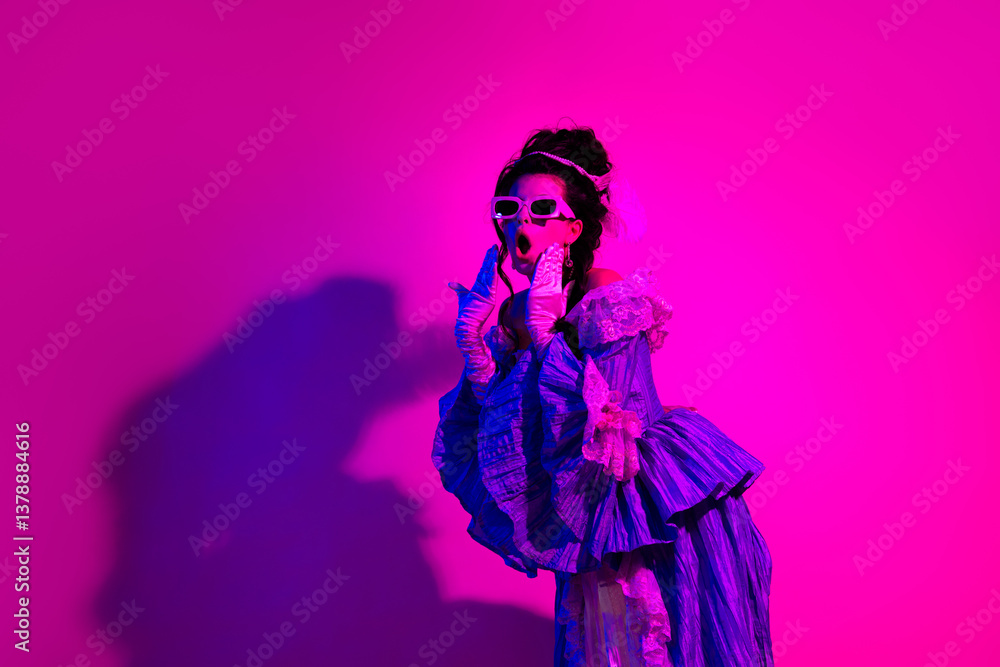 Fototapeta premium Elegant woman in royal costume posing in vibrant neon lighting with a pink backdrop