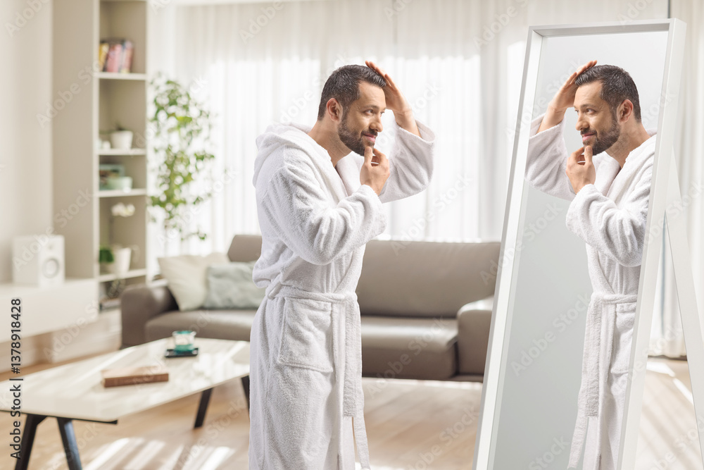 Man in a white bathrobe checking his hair and beard and looking at a mirror Man in a white bathrobe checking his hair and beard and looking at a mirror