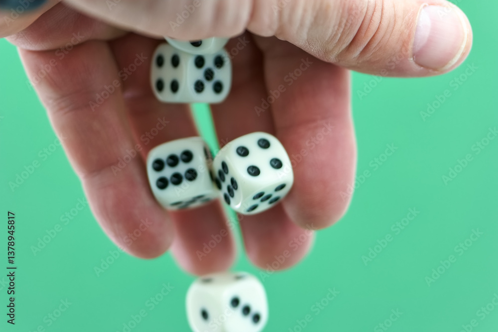 Hand dropping white dice with black dots on a green background d
