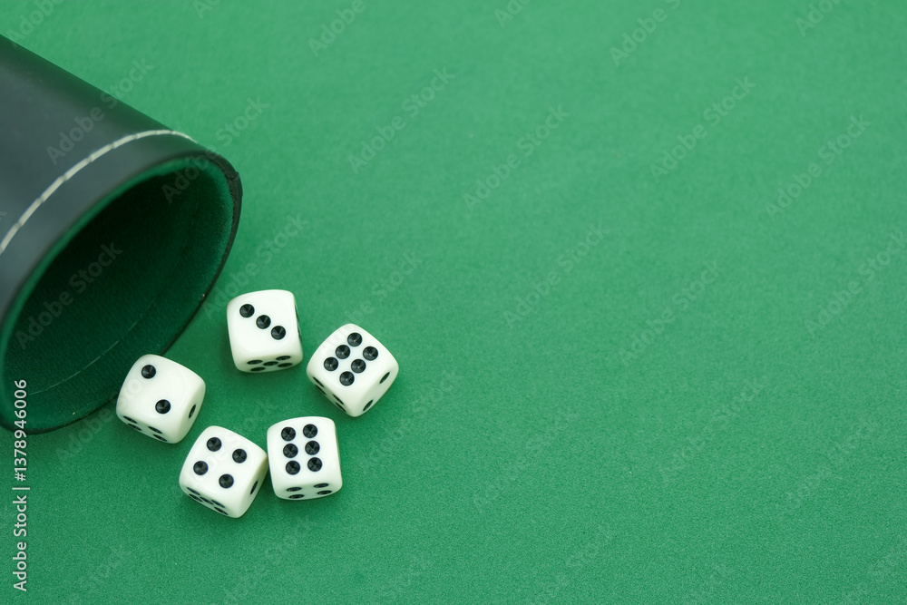 Classic dice rolled out of a leather cup onto a green felt surfa