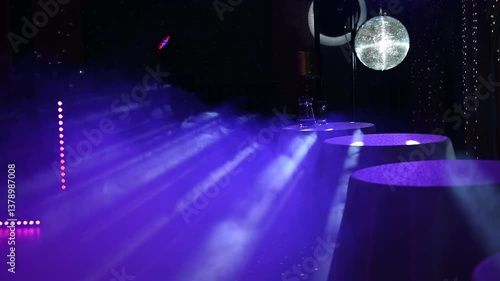 A mirrored disco ball reflects light rays throughout the room. Smoke enhances the visibility