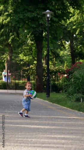 Wallpaper Mural Caucasian toddler playing with a ball in the park. Happy kid approaching camera carrying a ball. Vertical video Torontodigital.ca