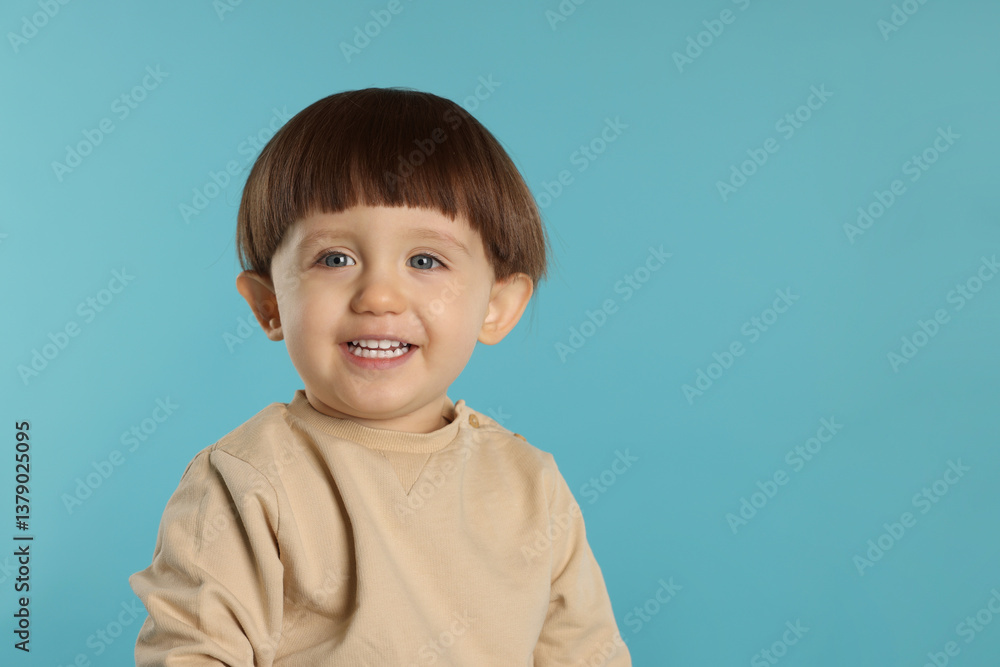 Portrait of happy little boy on light blue background. Space for text