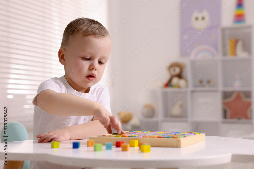 Motor skills development. Little boy playing with Times table tray indoors Motor skills development. Little boy playing with Times table tray indoors