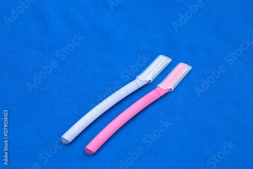 facial dermaplaning razors against blue backdrop