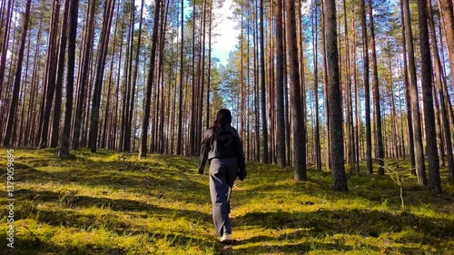 Back view follow shot of young woman walking trough forest in Latvia 