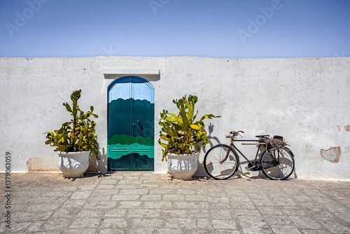 Fototapeta Naklejka Na Ścianę i Meble -  Scenic view of Ostuni, Italy's 'White City,' showcasing whitewashed buildings under a clear blue sky, with narrow streets and historic architecture illuminated by sunlight.