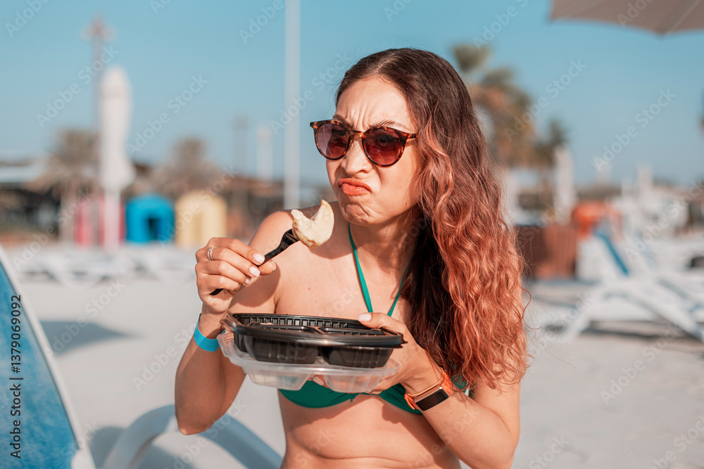 Tourist grimacing while eating takeaway food on a beach, expressing disgust and disappointment with the meal