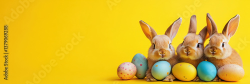 Cute bunnies with colorful Easter eggs on a yellow background