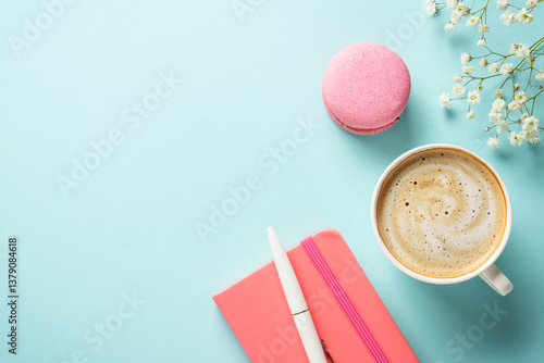 Cup of coffee, macaroon and flower on blue background.