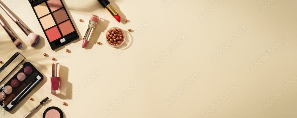 Make up products at colored background with hard shadows.