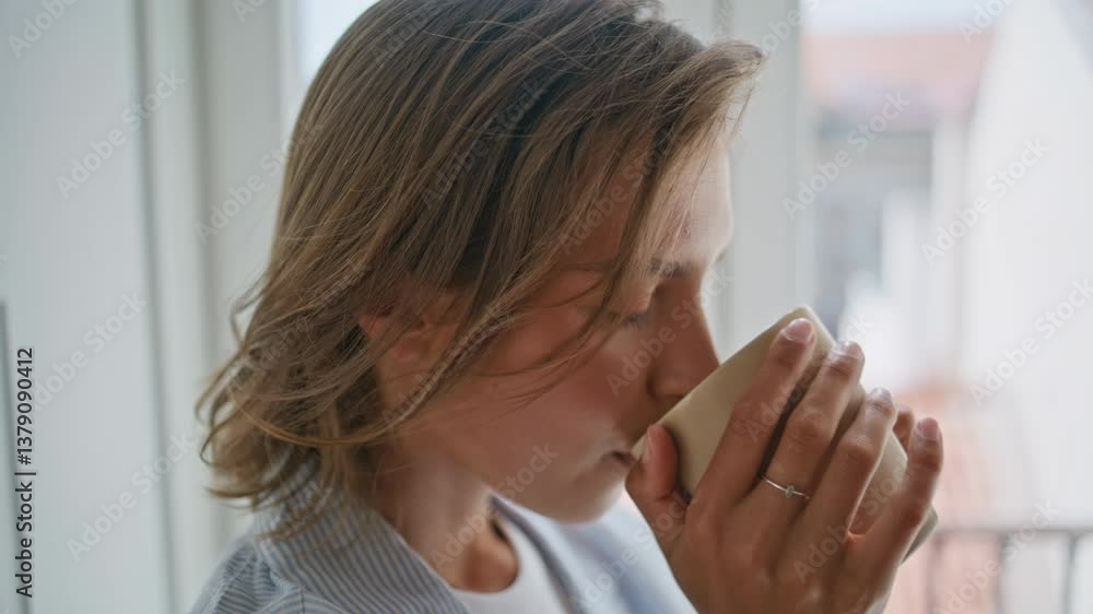 Closeup woman drinking coffee by home window. Satisfied lady tasting beverage Closeup woman drinking coffee by home window. Satisfied lady tasting beverage