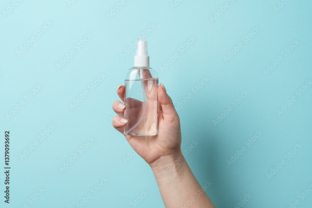 Cosmetic bottle in woman hand on blue background.