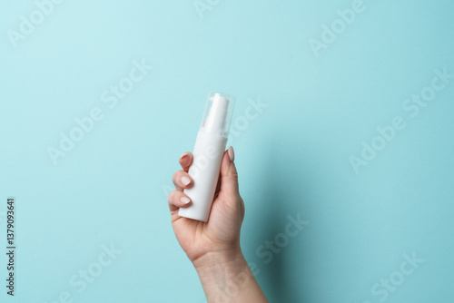 Obraz na płótnie Cosmetic bottle in woman hand on blue background. w salonie