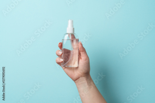 Obraz na płótnie Cosmetic bottle in woman hand on blue background. w salonie