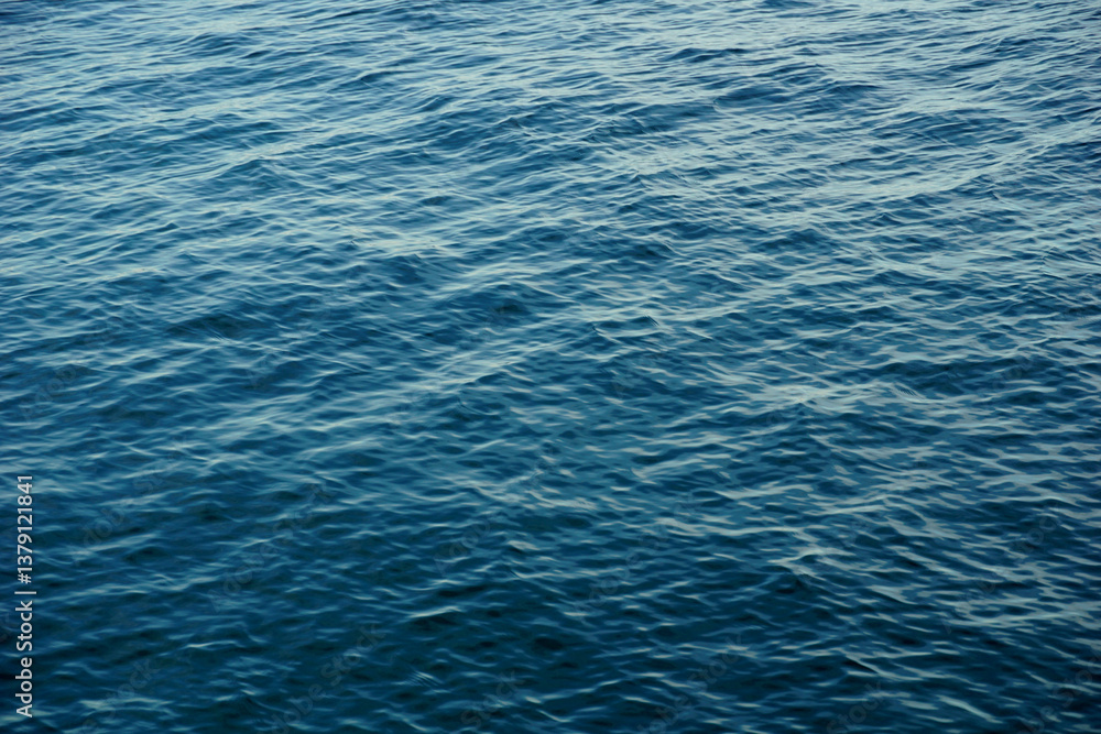 Fototapeta premium Shiny gradient blue sea surface with small waves and light reflection on the top of the water