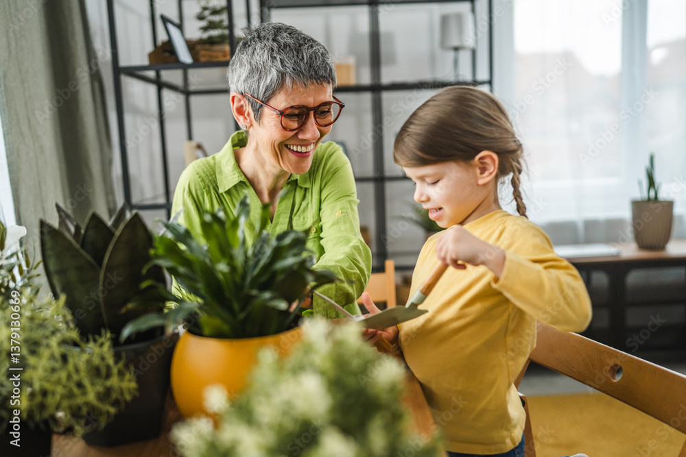 Obraz premium Grandmother with granddaughter transplant flowers at home
