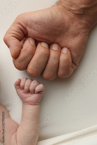 Two hands: man and child. Father and son touching fists. Dad and newborn son boys holding hands together. Little and big fists of father and son. 