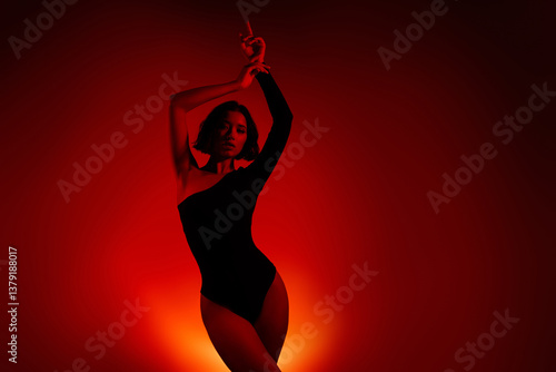 Stylish woman posing in silhouette with vibrant gradient orange and red light on background
