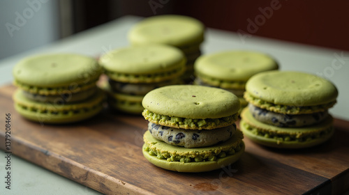 Group of six green macarons arranged on a wooden cutting board.