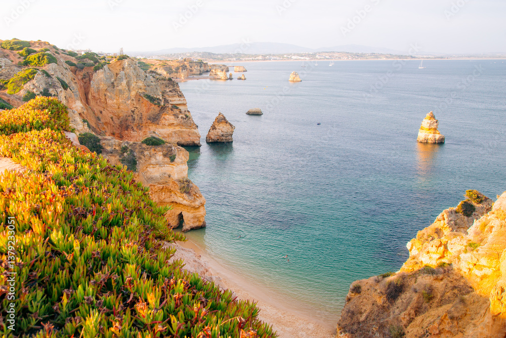Scenic Algarve coastline: Cliffs, beach, and turquoise water attract tourists for relaxation