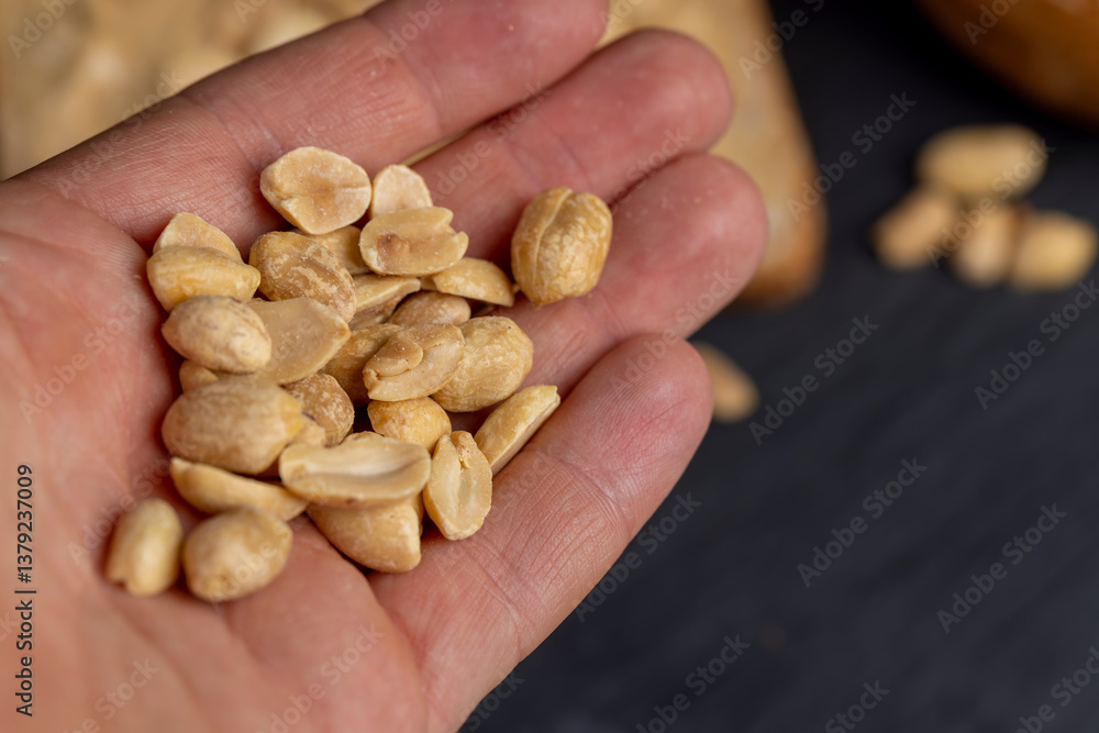 peanut butter on a piece of bread and roasted peanuts on the table