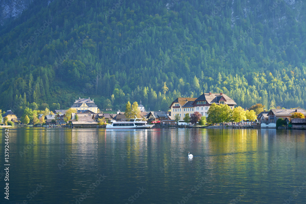 Fototapeta premium Tour Boat at Dock Hallstatt Austria. A tourist passenger boat docks in beautiful Hallstatt, Austria as a swan glides by.