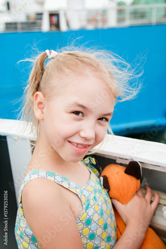 Close-up portrait of a smiling girl with pigtails and windblown hair on a cloudy beach day photo