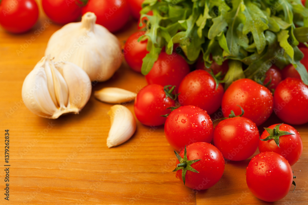 Tomatoes, garlic and rucola on wooden table, focus on foreground