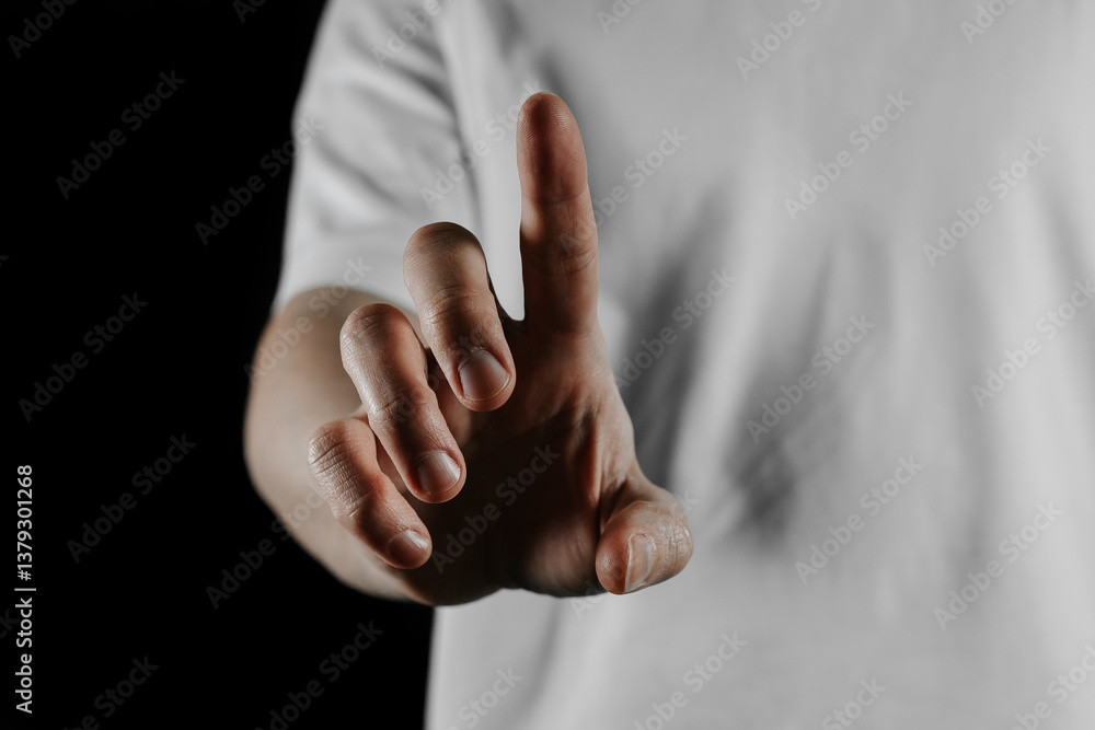 Obraz premium Close-up of human hand pointing with index finger on black background. Gesture of direction, touch or attention. Concept of choice, decision, interaction, touchscreen or communication.