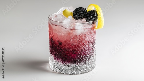 Refreshing purple cocktail with blackberries and lemon twist in textured glass