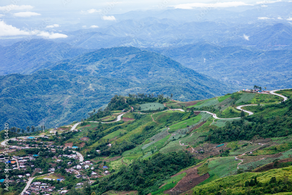 Fototapeta premium Scenic mountain road curves through lush green hills aerial view nature landscape in countryside environment