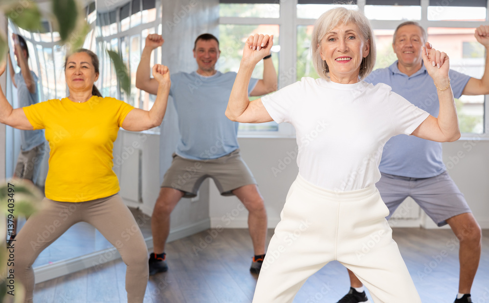 Fototapeta premium Group of aged people rehearsing sports dance in dance hall