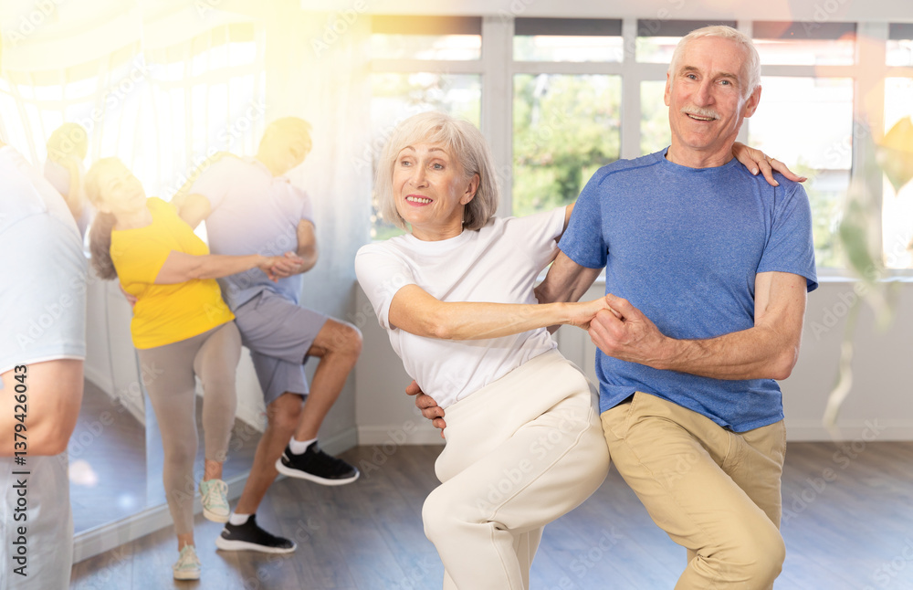 Obraz premium Couple of elderly man and elderly woman dancing twist in studio