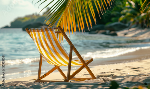 Obraz na płótnie Close-up of a striped beach chair on a sandy beach, with palm leaves and the ocean in the background. w salonie