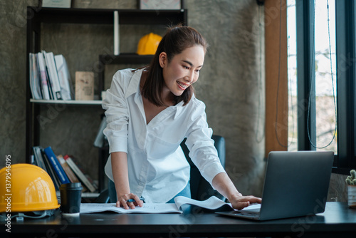 Картината върху платно Female architect in a modern office reviewing blueprints, showcasing professionalism and creativity in an industrial setting