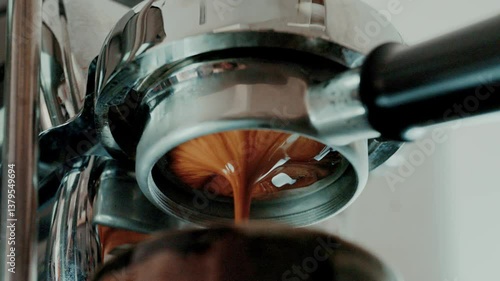 Pouring coffee stream from professional machine in cup. Barista man making double espresso, using filter holder. Flowing fresh ground coffee. 