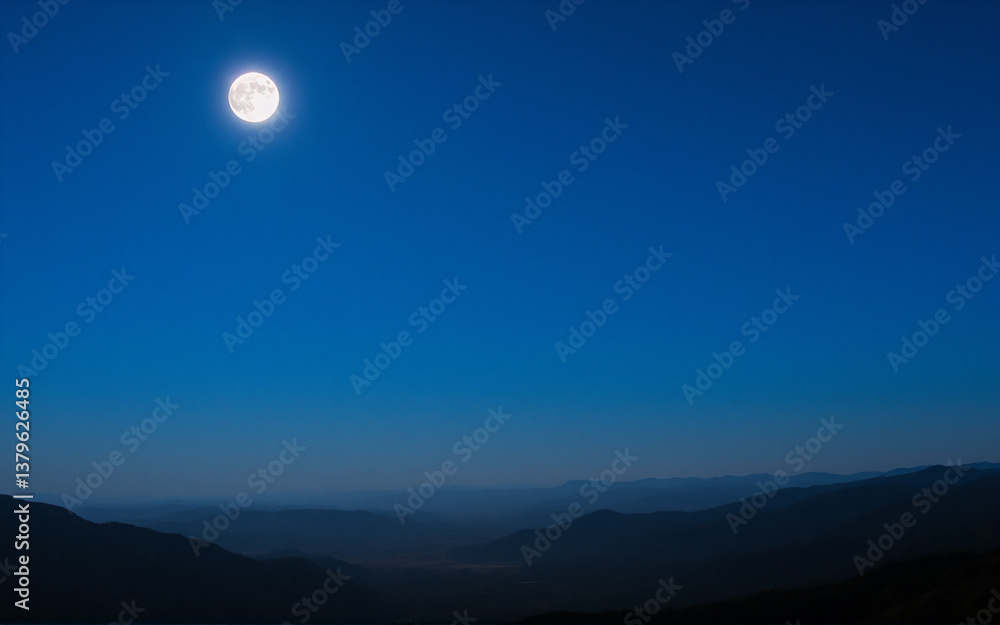 Full moon illuminates a dark mountain range under a gradient blue night sky. A tranquil and peaceful scene of nature at night. Full moon illuminates a dark mountain range under a gradient blue night sky. A tranquil and peaceful scene of nature at night.