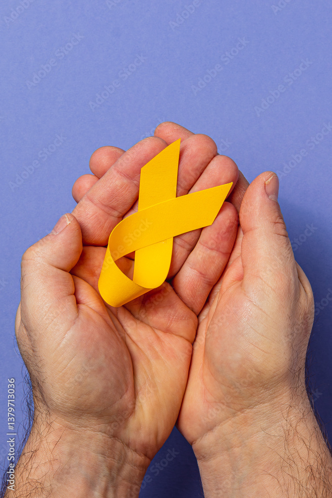 Hands holding a yellow ribbon symbolizing cancer awareness and support Hands holding a yellow ribbon symbolizing cancer awareness and support