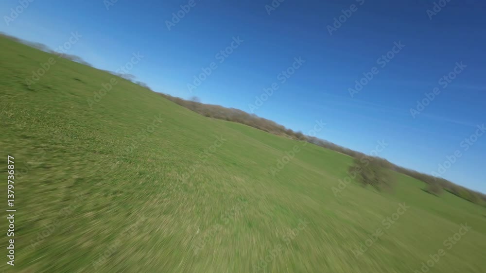 FPV aerial drone close proximity flying close across rural fields and around trees in England sunny day. FPV aerial drone close proximity flying close across rural fields and around trees in England sunny day.
