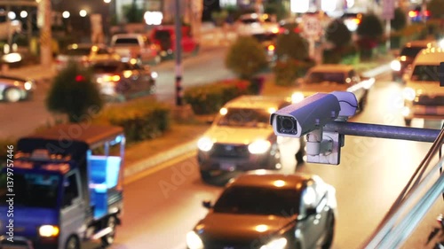 City traffic monitoring camera and speed control above the asphalt road with many blurred cars at night. 