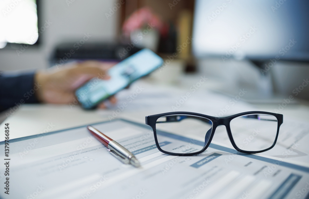 © Lek - close up shot and select focus on eyeglasses, blur background hand of businessman using phone and working with computer, concept looking to the future for success business plan