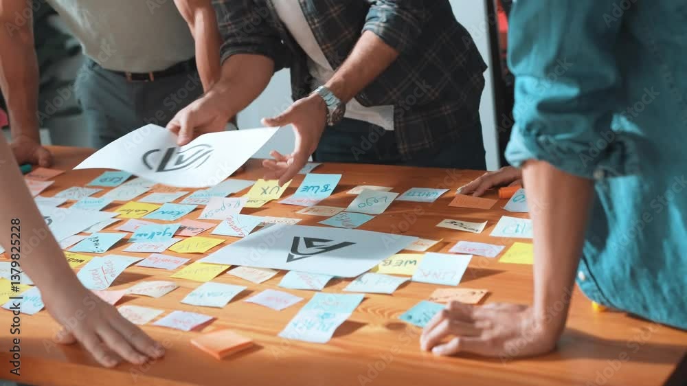 Close up of designer hands design logo graphic together at meeting. Professional graphic working together and brainstorming idea about product design at table with colorful sticky notes. Symposium. Close up of designer hands design logo graphic together at meeting. Professional graphic working together and brainstorming idea about product design at table with colorful sticky notes. Symposium.